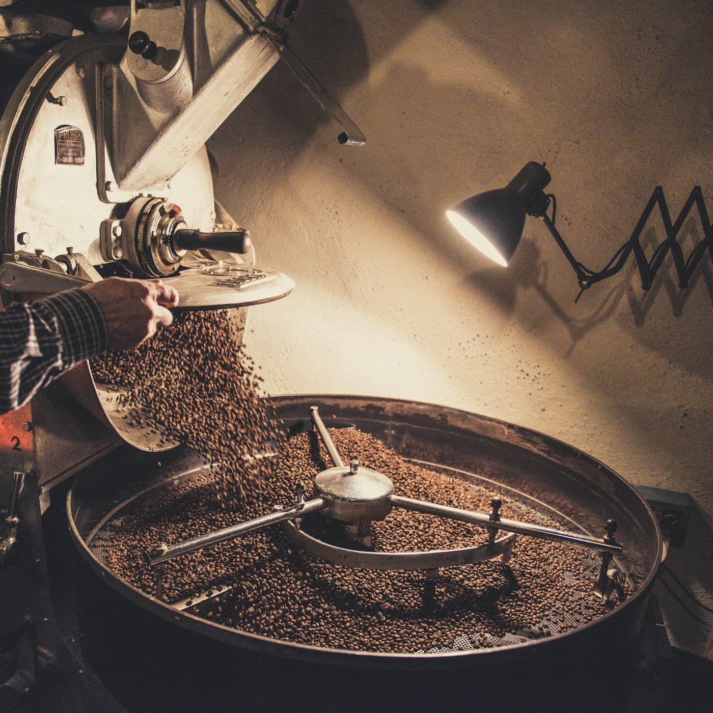 The drum roaster mid-batch, beans tumbling behind the glass.